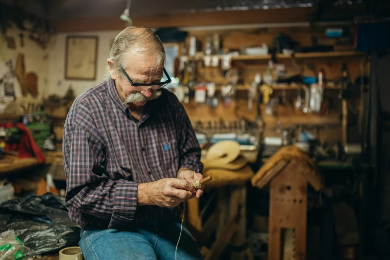 a man who is knitting is wearing a pair of glasses