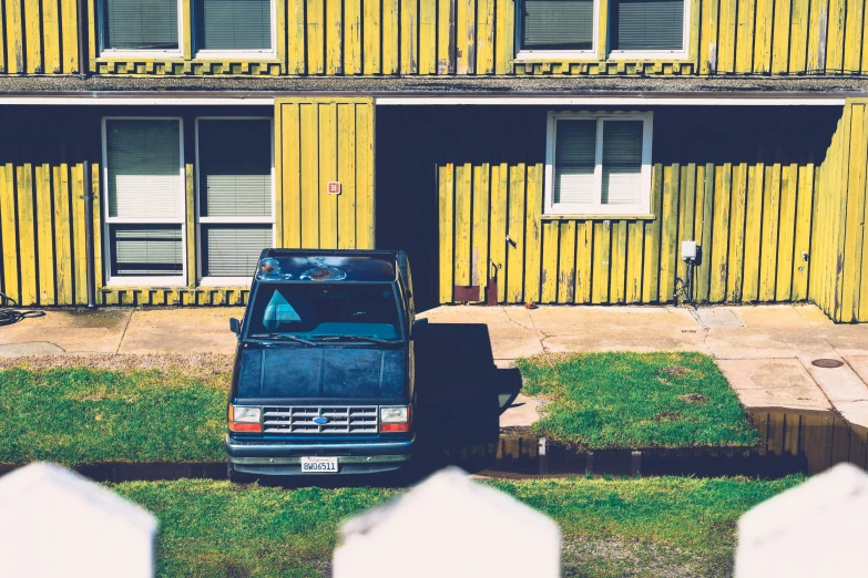 an old, blue van is parked in front of a building with windows