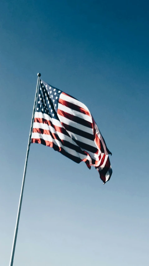 an american flag is fluttering on a pole