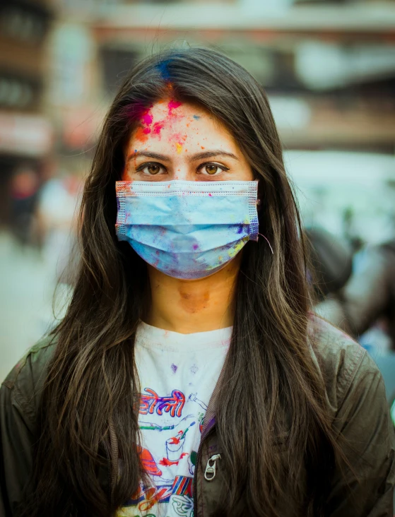 a young woman in a face mask covered with colorful powder