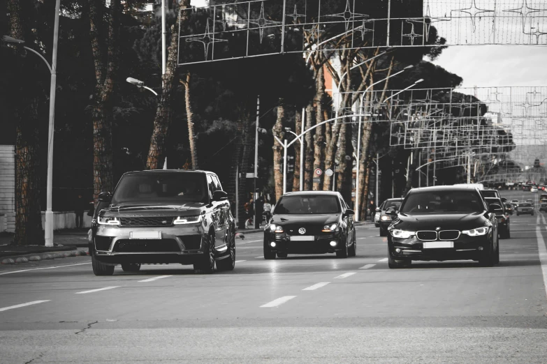 three cars in traffic on the road with trees in background