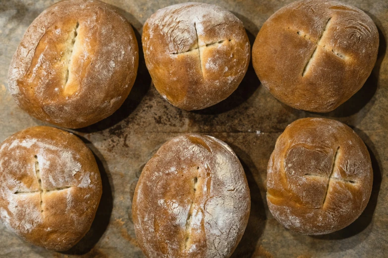 four bread rolls placed in a square formation on top of parchment