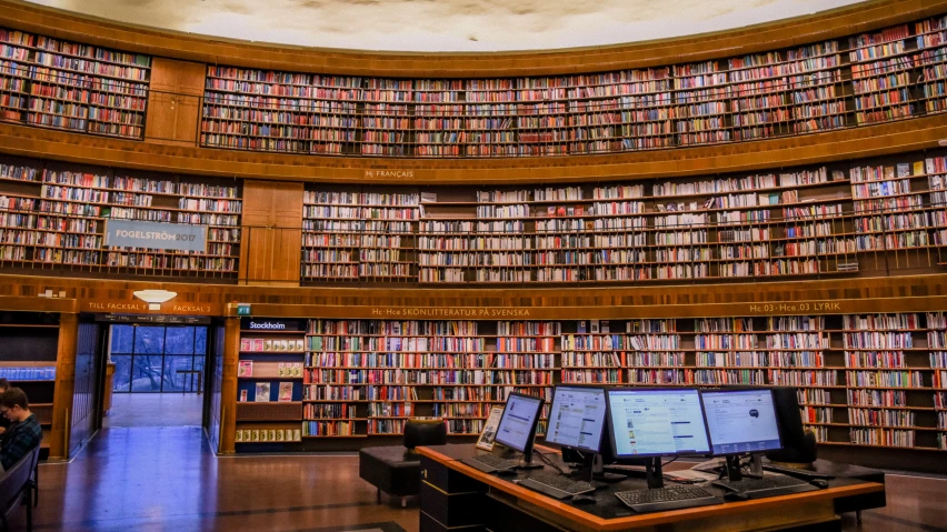 the circular room is full of books in which computers are on