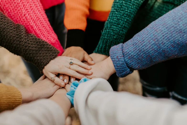 people in multi - colored outfits holding hands together