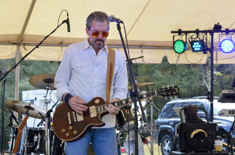 the man is playing the guitar outside on the stage