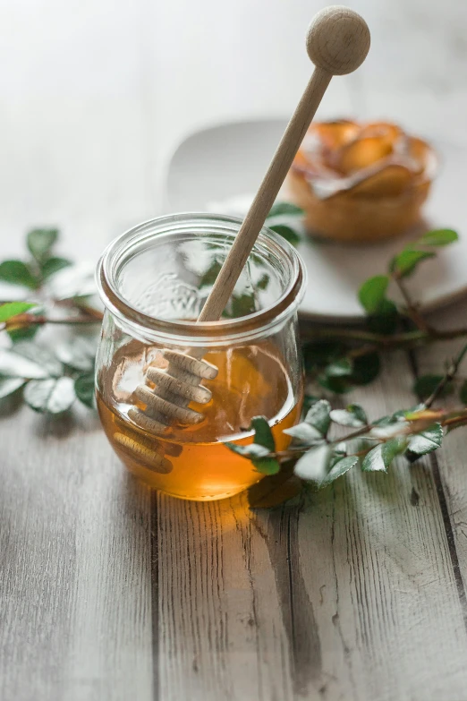 a jar of honey with two wooden spoons inside