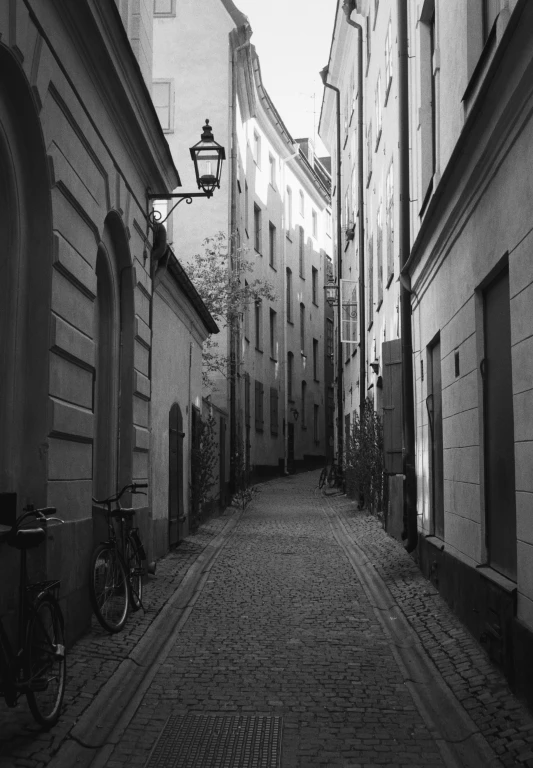 a black and white image of a city street with a bike leaning against the wall