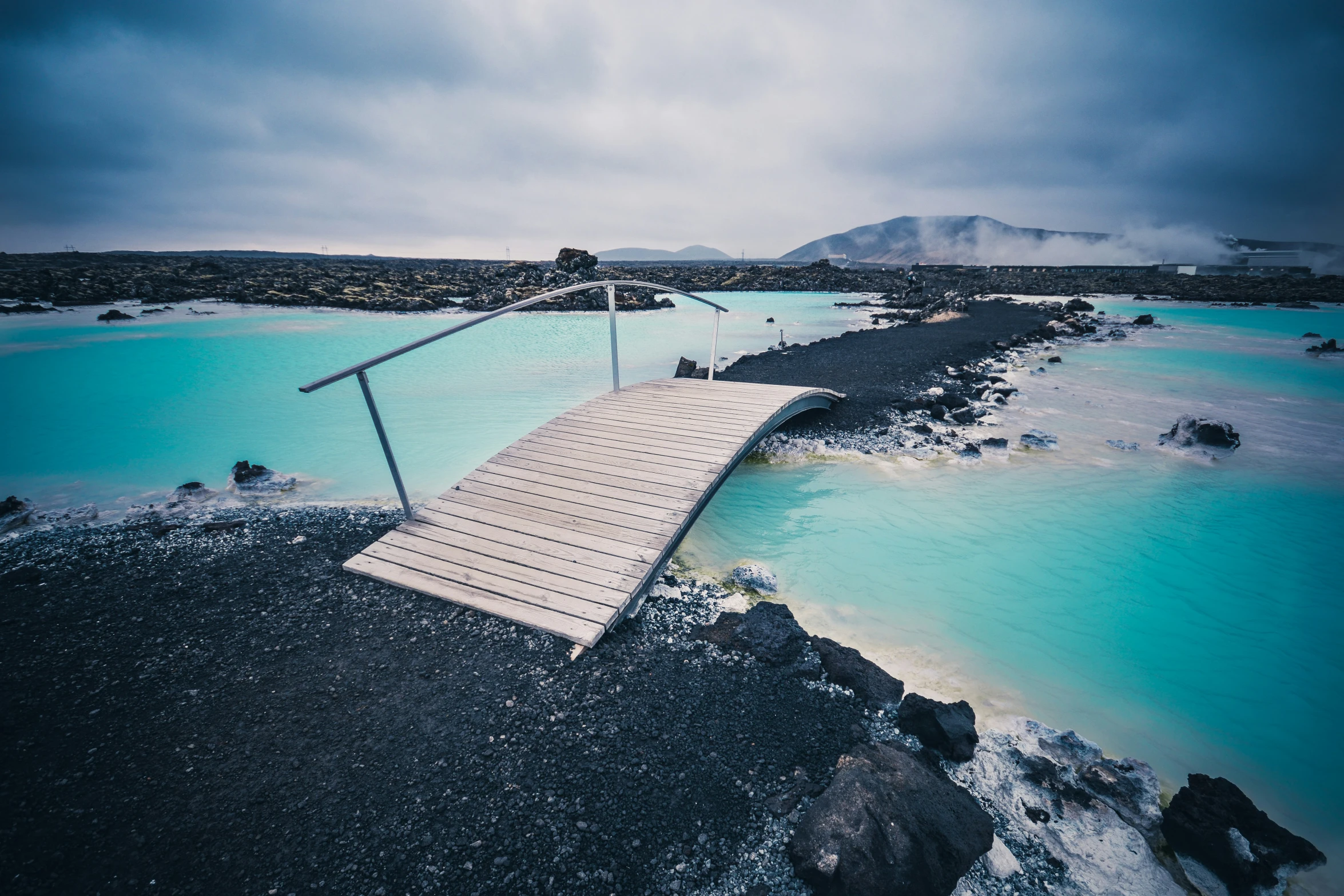 a blue lagoon with a boardwalk leading to the top