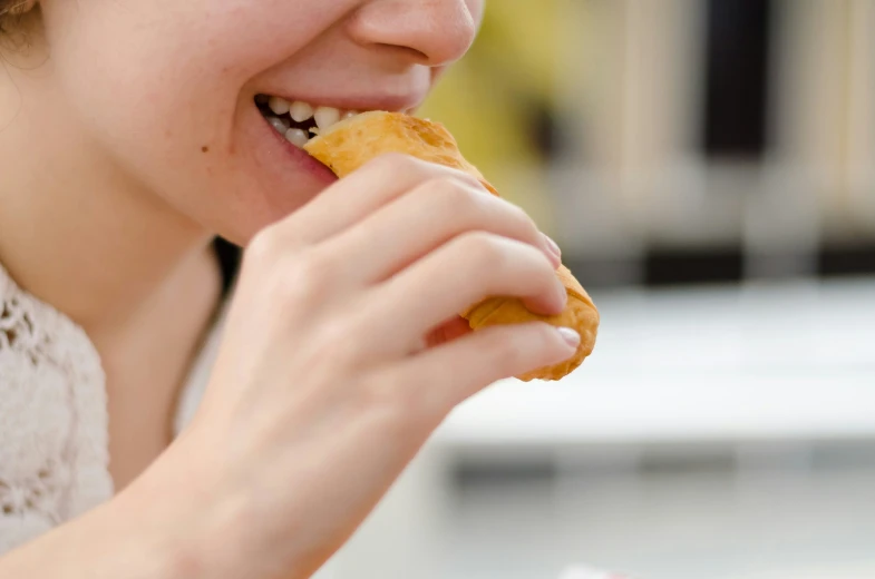 woman eating pastry outside smiling at camera