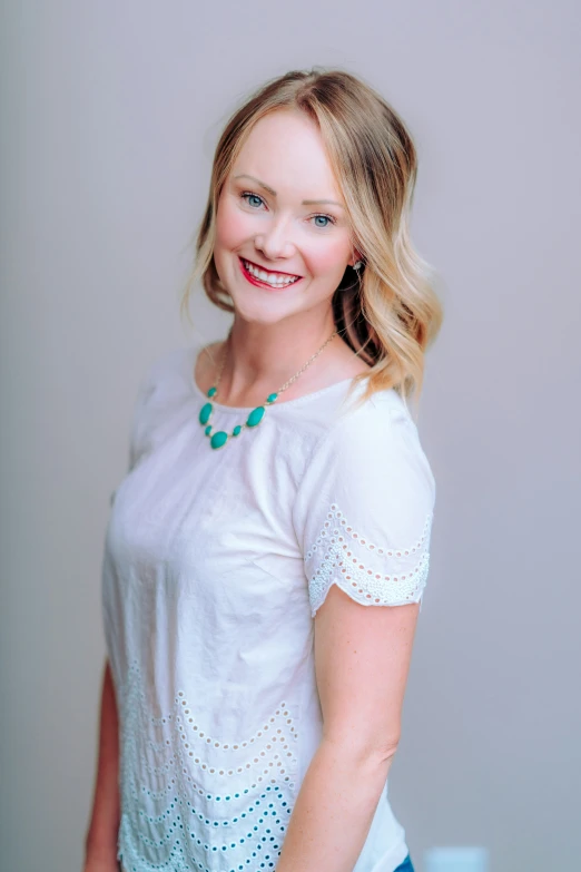 a woman in a white top smiles at the camera