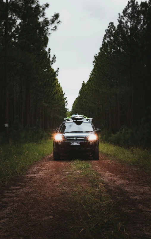 a car with its lights on sitting in the middle of the road