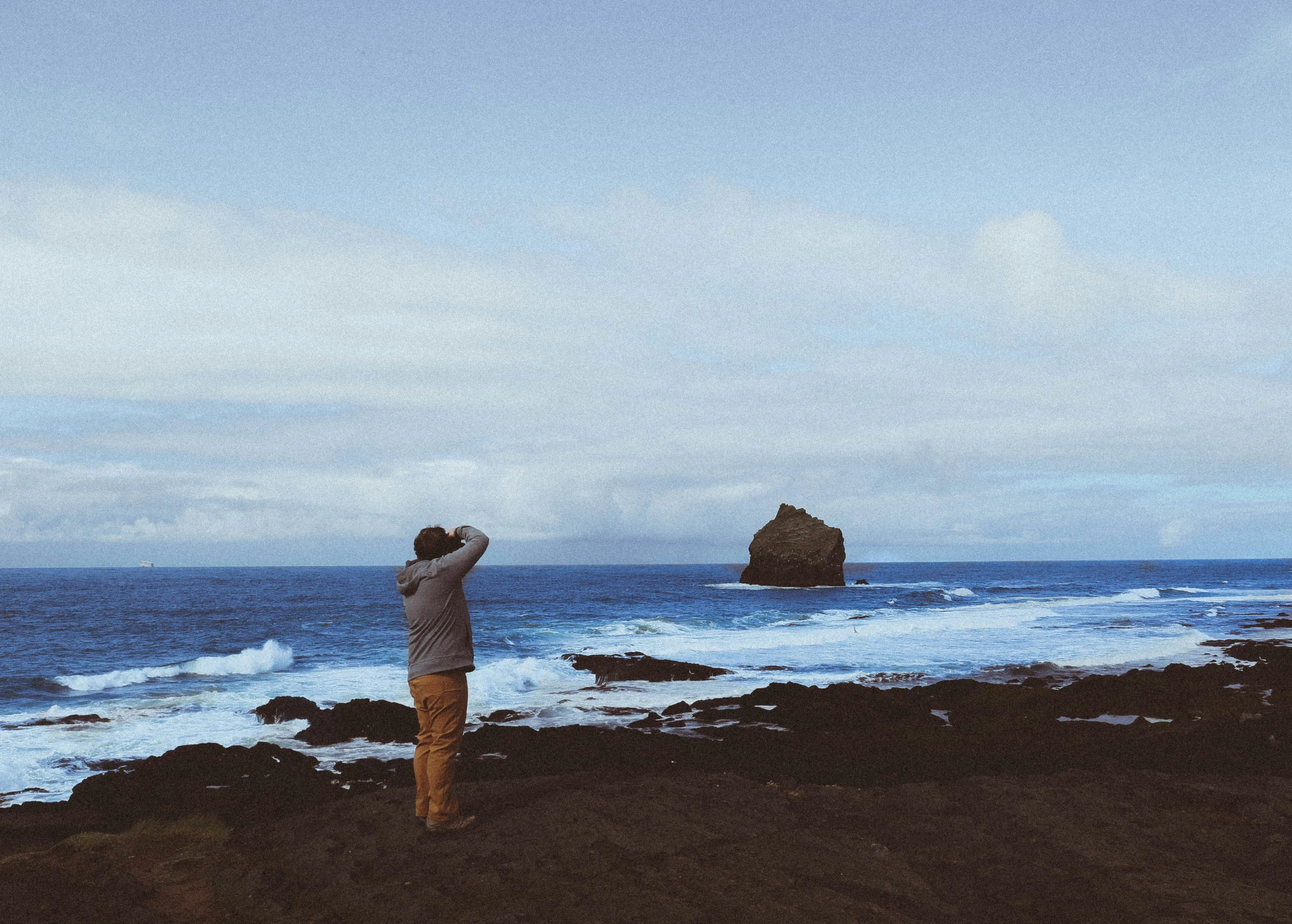 a person is standing at the beach flying a kite