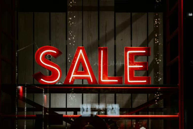 a red sale sign is seen behind the metal display rack