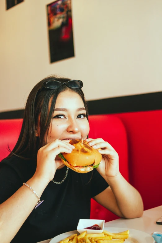 the woman in glasses is eating a hamburger