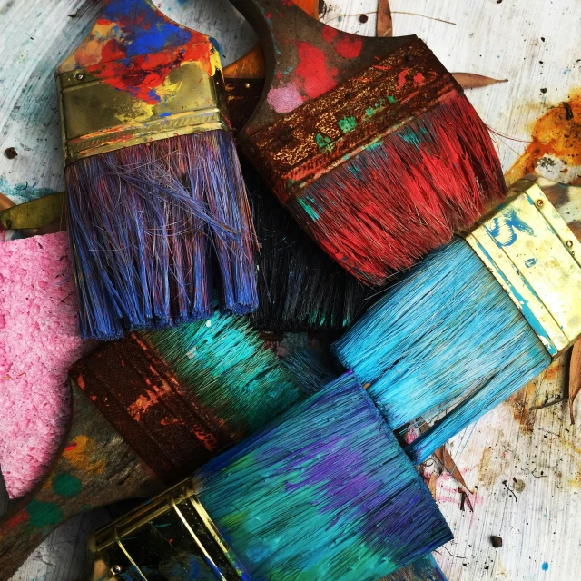 colorful brushes are sitting on a table and scattered about