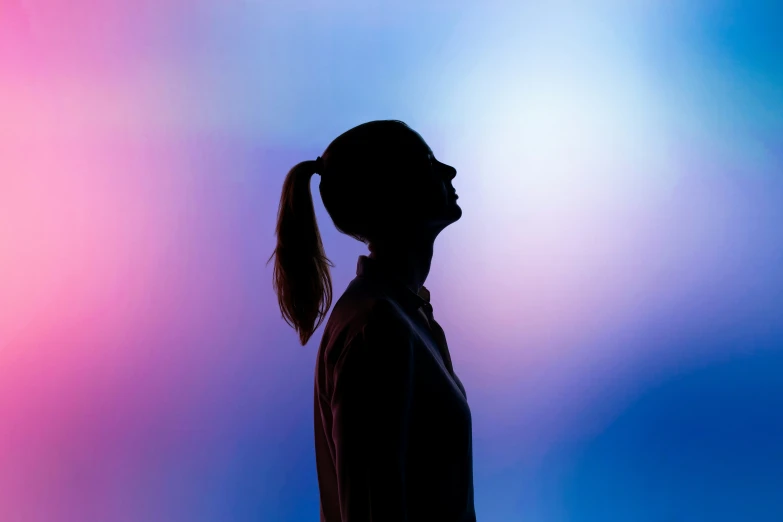 a silhouette of a woman with a ponytail in front of a blue and pink background