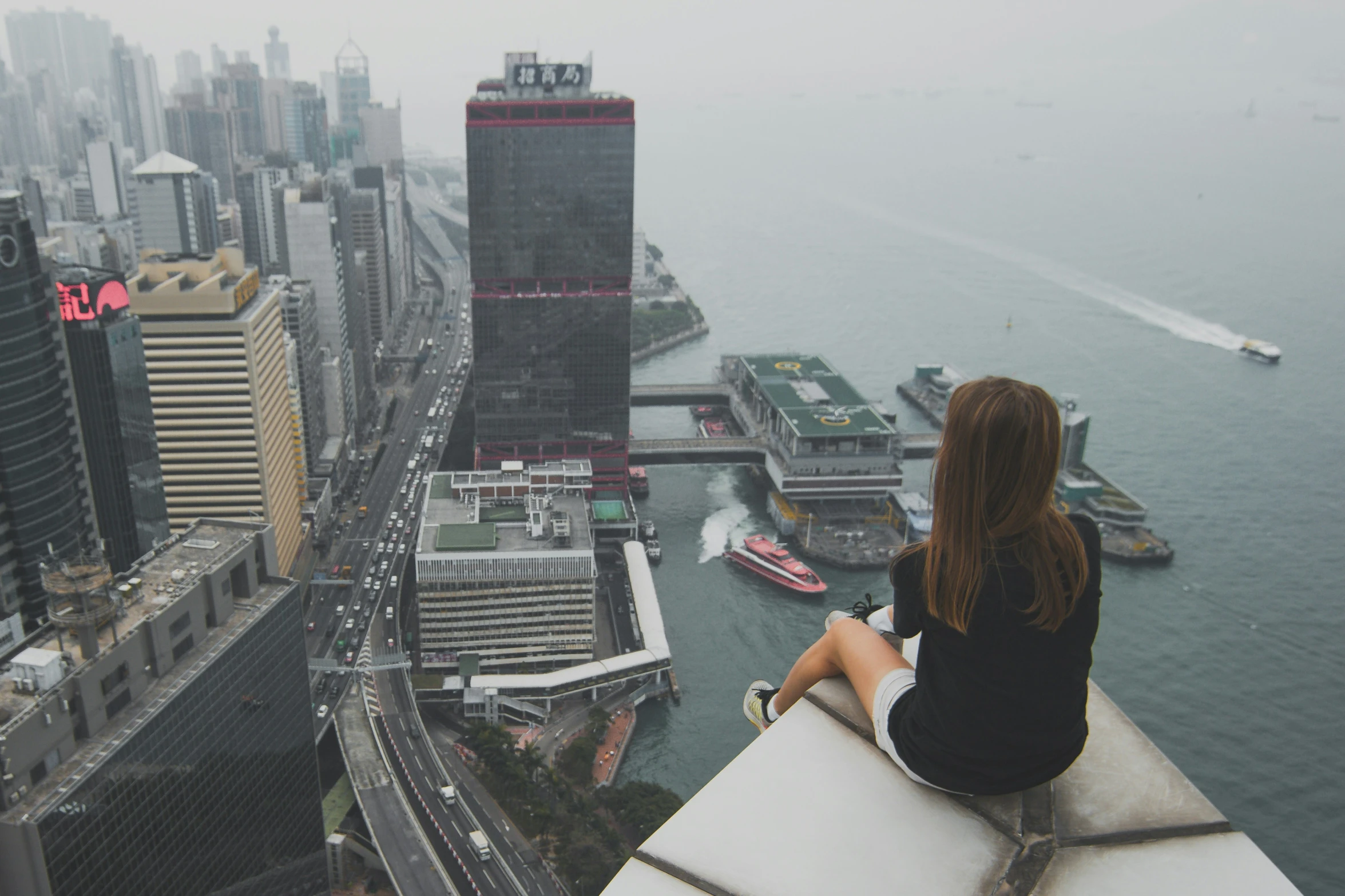 a woman sitting on a building looking over the city