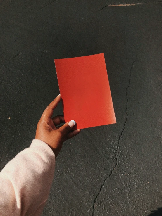 a person holding a red square item over a parking lot