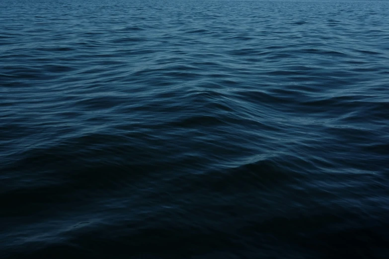 a view of the blue ocean waves with a sailboat in the distance