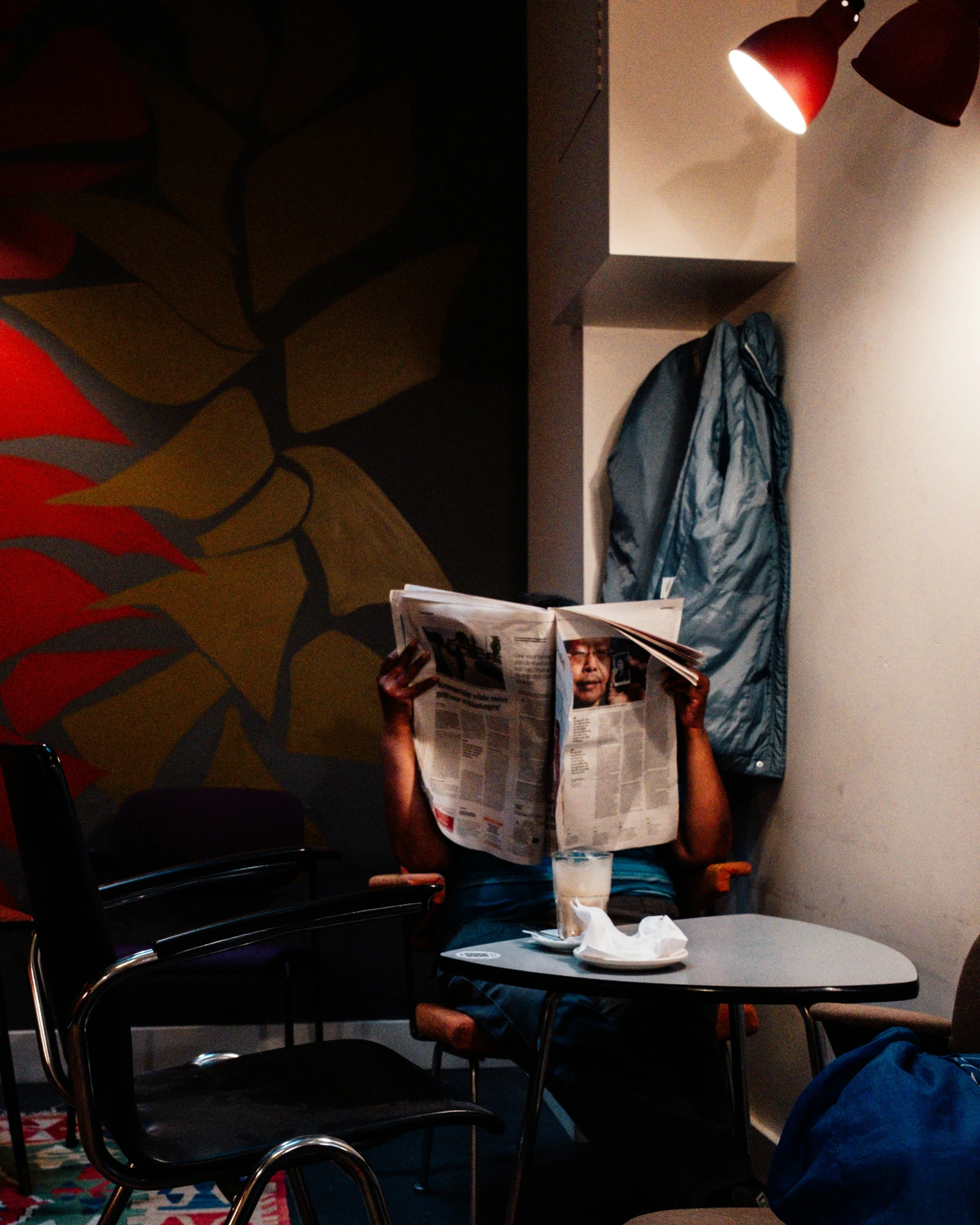 a person sitting at a table reading a newspaper