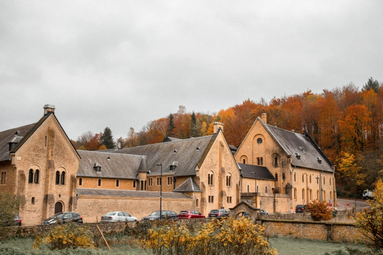 the building with the roof in the middle is next to a wall with trees in front of it