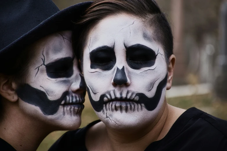 two people wearing white faces and skulls painted on them