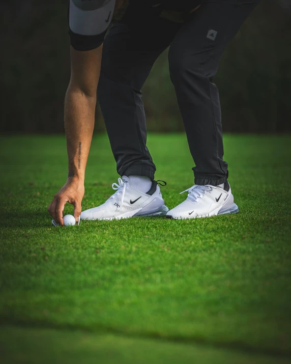 a man is standing in the grass on his feet and golf balls