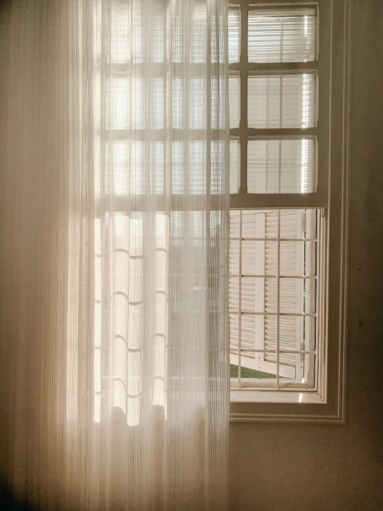 an open window with white curtains sitting in front of a curtain