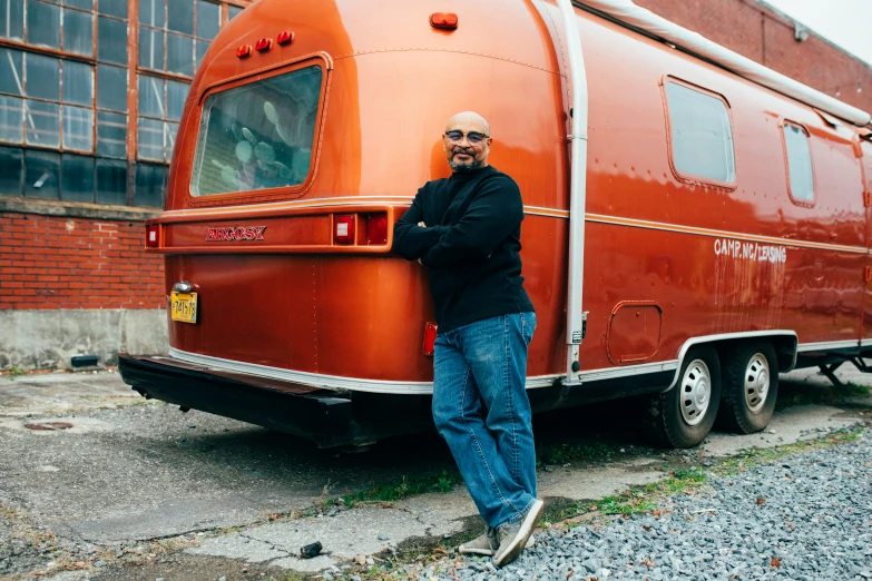 an old man standing next to an orange vehicle