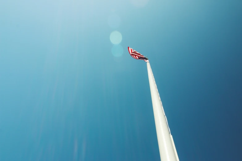 an american flag on top of a tall white pole