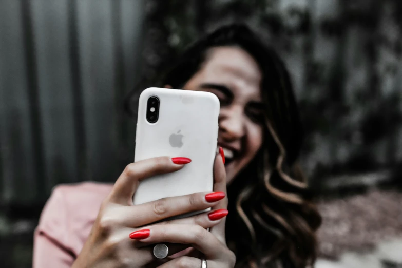 a young woman wearing a red and white nail polish holding a phone