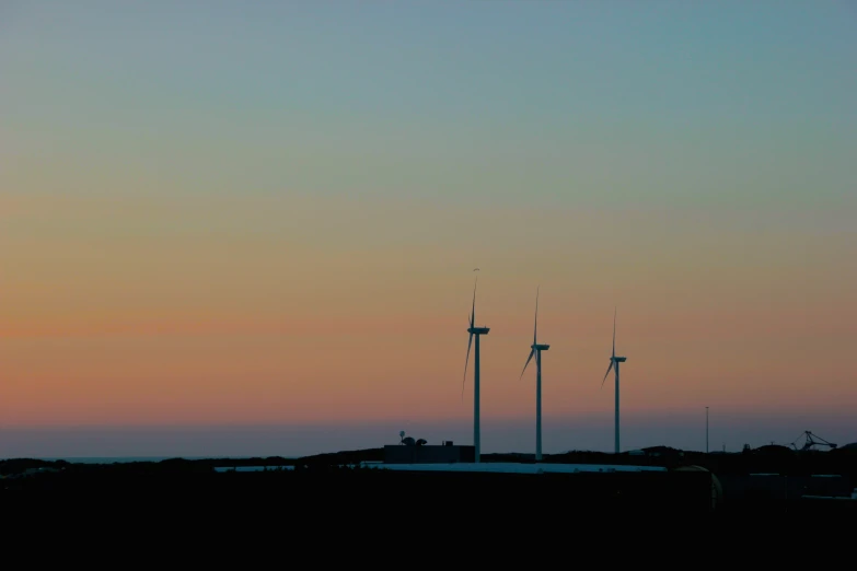 a group of windmills are silhouetted against the sunset