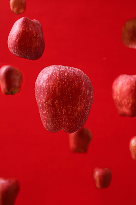 a red background with some apples in the air