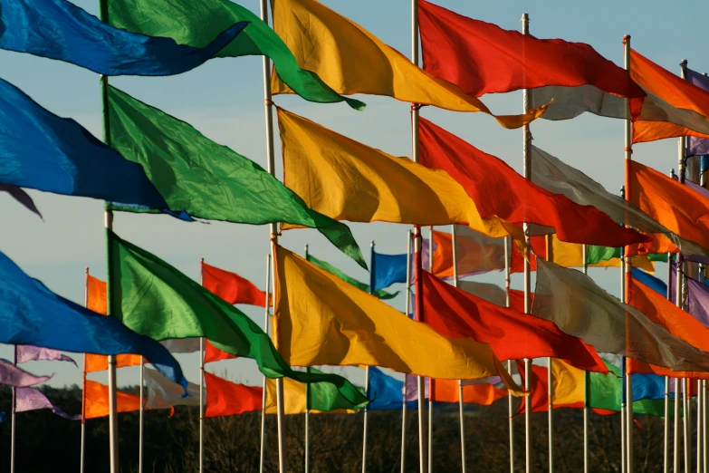a group of large multi - colored flags on poles