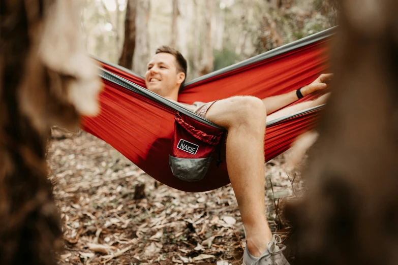 man in a red hammock smiles for the camera