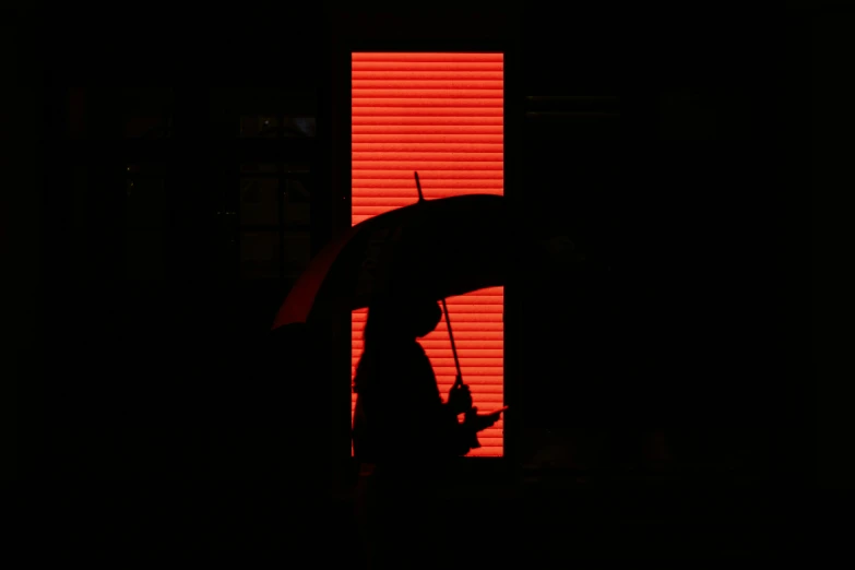 the silhouette of someone holding an umbrella against a bright light