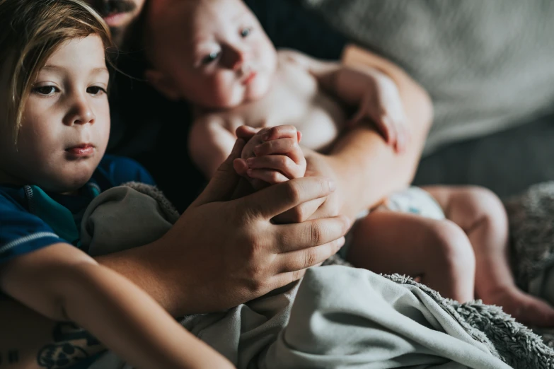 two children hold the hand of someone holding their hand