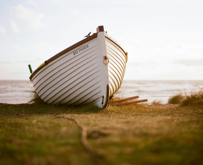 a boat sitting on top of green grass next to the ocean