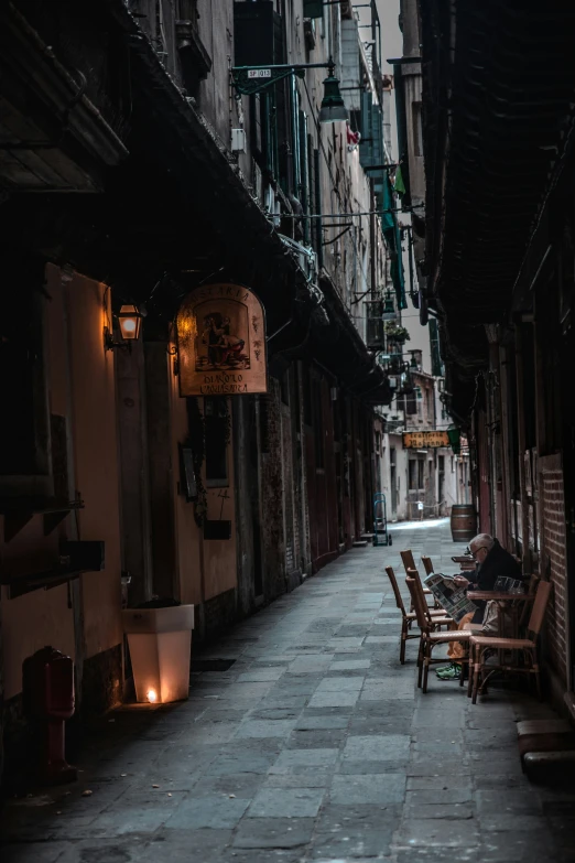 several tables and chairs in a dark alley with lights