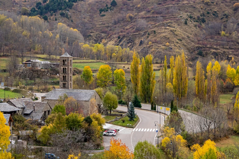 a road runs through an old village with fall colored trees