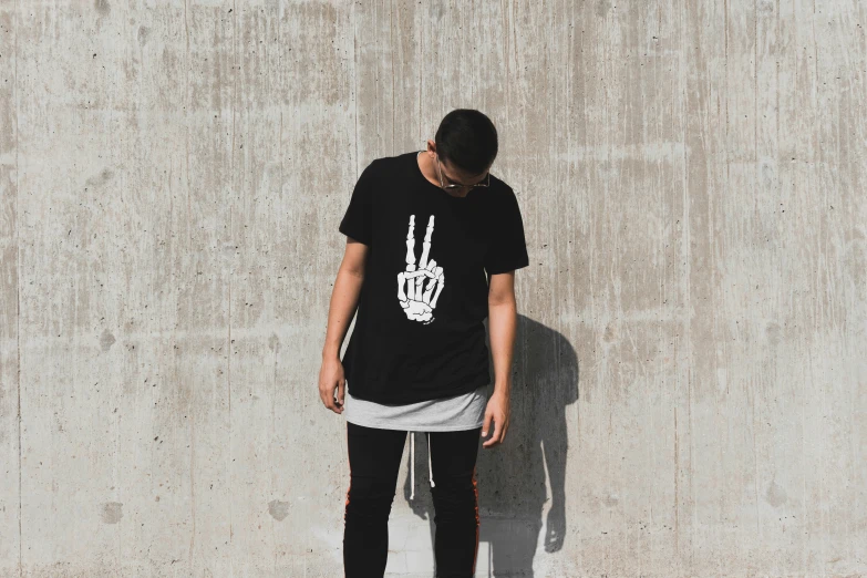 a man stands against the wall with a hand peace sign on his shirt