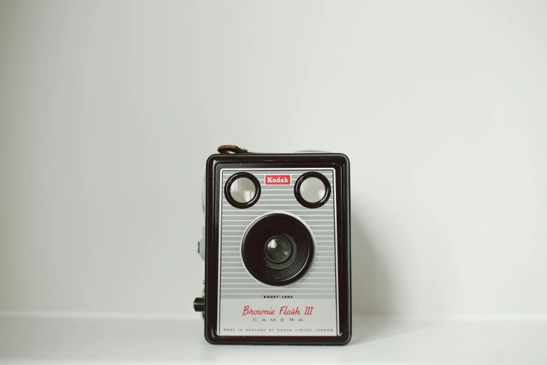 an old fashioned camera on the floor in front of a white wall