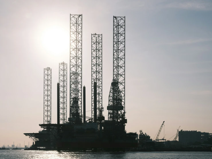 large offshore rigs sit in the water at sunset
