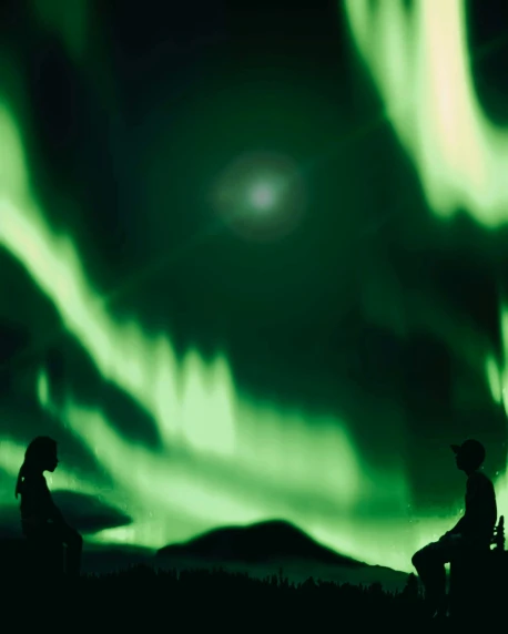 two people sitting on a bench watching the aurora or northern lights