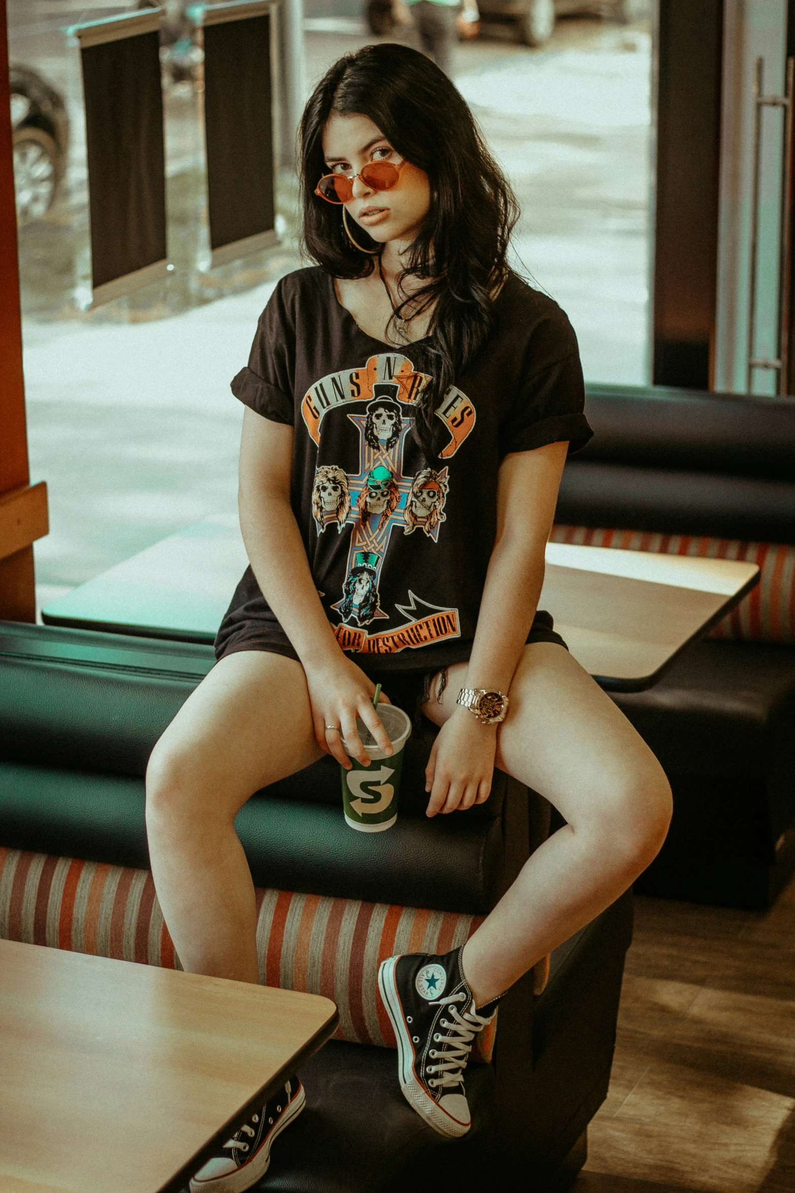 girl in black shirt sitting on striped couch next to window