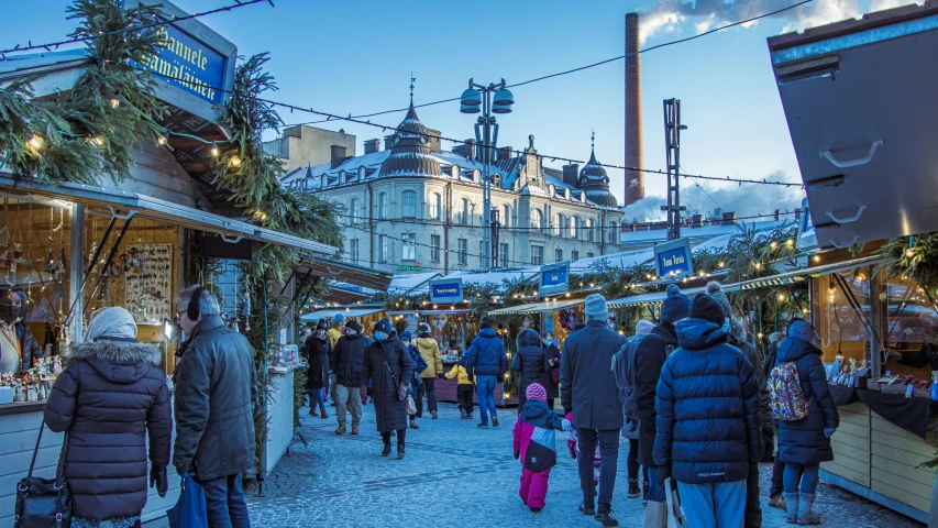 people walk through an outdoor marketplace with a christmas tree in the foreground