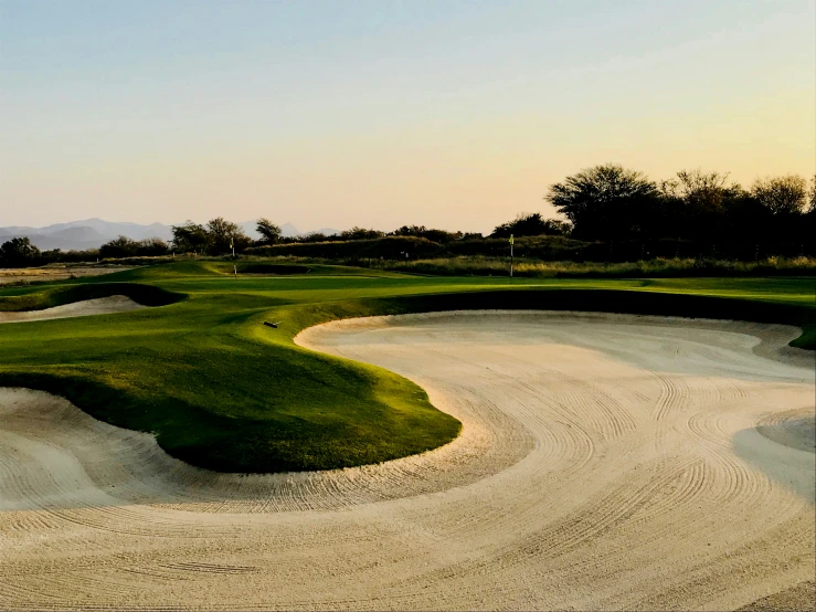 a sand track next to the green of a golf course