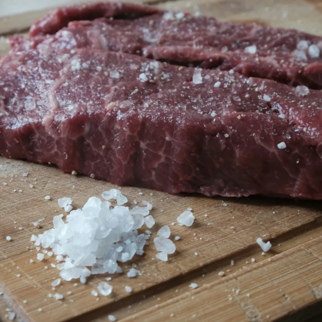 a close up of a piece of meat on a  board with food