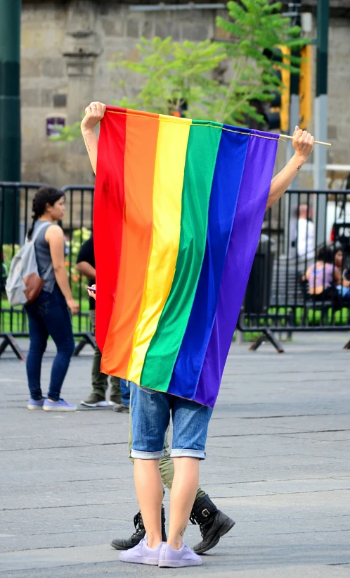 a person holds a rainbow flag at the city square