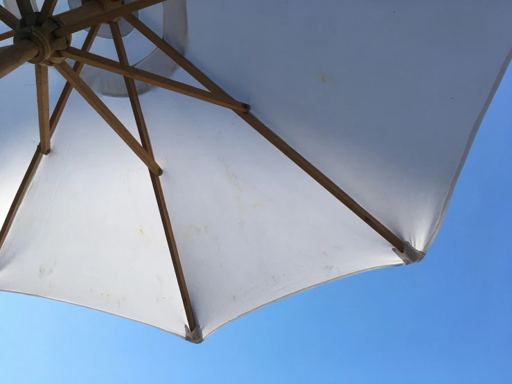 an umbrella and blue sky with wicker poles